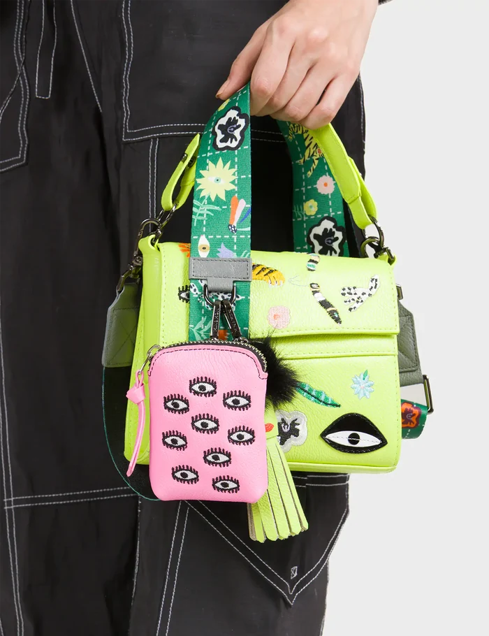 Person holding a colorful handbag with a matching small pouch featuring eye designs.