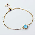 Gold penis bracelet with a blue gemstone on a white background