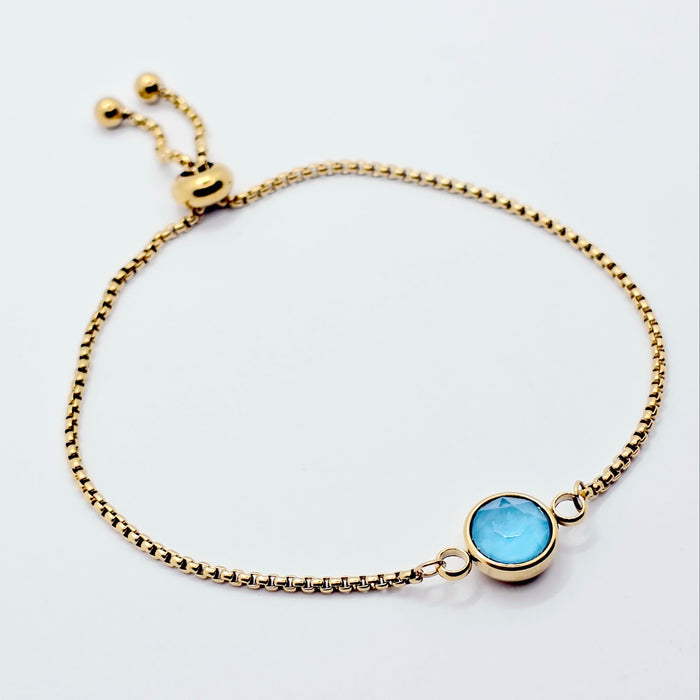 Gold penis bracelet with a blue gemstone on a white background