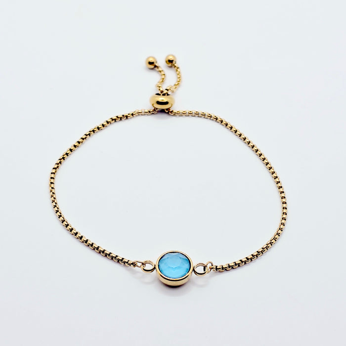 Gold penis bracelet with a blue gemstone on a white background
