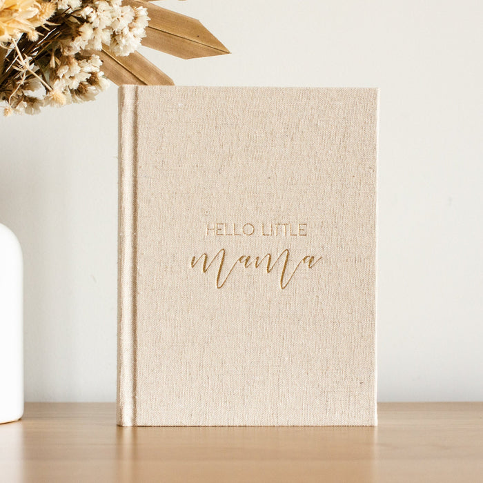 A Photo of a sand linen journal with gold writing on the front saying 'Hello Little Mama'. This journal is for the Mother to be to write in about her pregnancy journey.
